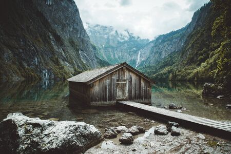 Panoramic view traditional old wooden boat house at scenic Lake Obersee on a beautiful day with blue sky and clouds in summer, Bavaria, Germanyのeditorial素材