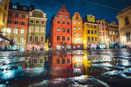 Classic view of colorful houses at famous Stortorget town square in Stockholm's historic Gamla Stan (Old Town) reflecting in a puddle at night, central Stockholm, Swedenの写真素材