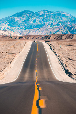 Classic panorama view of an endless straight road running through the barren scenery of Death Valley...