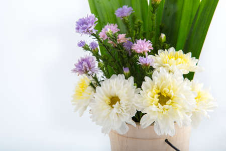 Colorful flowers in the wooden bucket on the white backgroundの写真素材