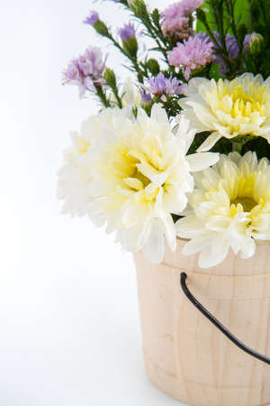 Colorful flowers in the wooden bucket on the white backgroundの写真素材