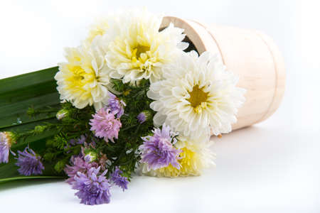 Colorful flowers in the wooden bucket on the white backgroundの写真素材