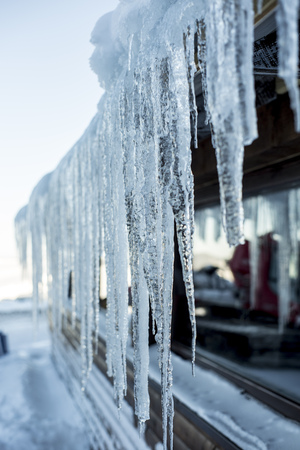 Big icicles stretching from a roof of a house  on a freezing cold winter dayの写真素材