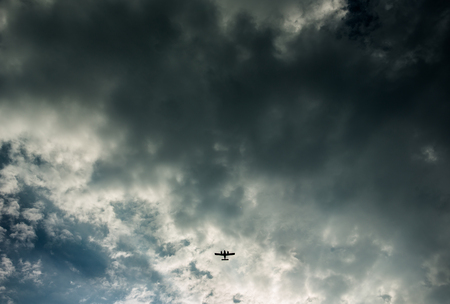 Airplane in clouds with sun rays breaking trough cloudsの写真素材