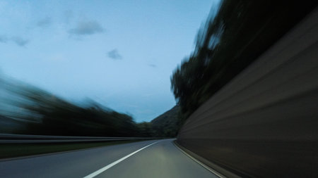 Driving car on a highway surrounded with trees , with a beautiful sky in the background