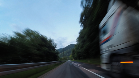 Driving car on a highway surrounded with trees , with a beautiful sky in the backgroundの写真素材
