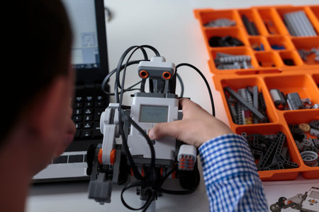 Intelligent kid , working on laptop after constructing robot, programming a robot