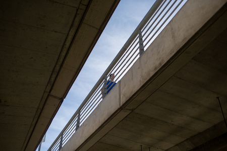 Male athlete running on a bridge, urban scenety,  viewed from belowの写真素材