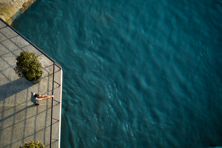 Overhead view of male athlete stretching his leg on a railing, beside a riverの写真素材