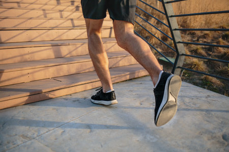 Male athlete climbing up the stairs beside a river, urban scenery