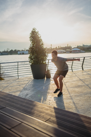 Male athlete doing box jumps in an urban scenery, beside a riverの写真素材