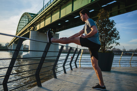 Male athlete stretching his leg on a railing