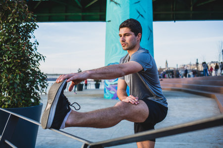 Male athlete stretching his leg on a railingの写真素材