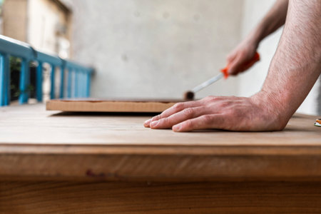 Man painting (dye) wooden plank with a roller