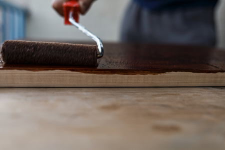 Man painting (dye) wooden plank with a rollerの写真素材