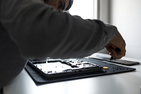 Computer repair technician working on a laptop with small toolsの写真素材