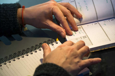 hand with a fountain pen making notes on a calendarの写真素材