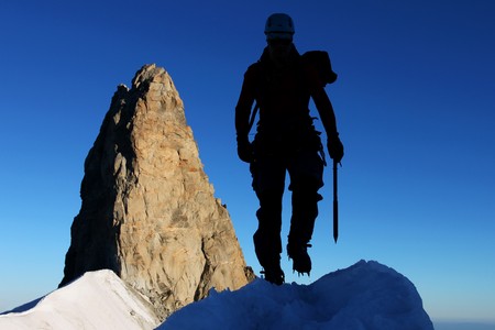 Silhouette of a mountaineer with rocky pinnacle in the backgroundの写真素材