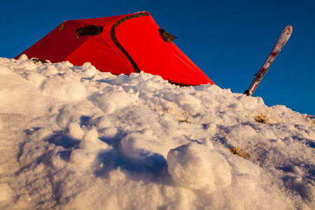 Red tent set on a snow slopeの写真素材
