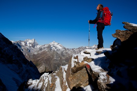 Young man with backpack enjoying the view from a mountain ridgeの写真素材