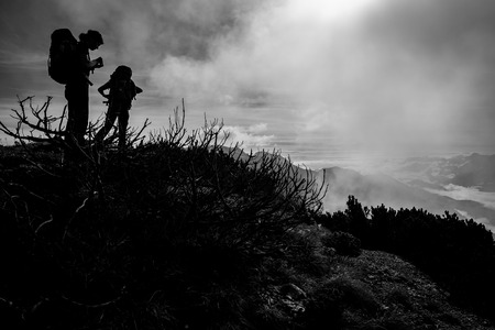 Silhouttes of two women with backpacks on an autumn mountain hikeの写真素材