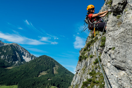 Young woman in helmet climbing via ferrata in  Austrian Alpsの写真素材