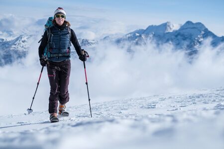 Young woman on skis ascending the mountain slopeの写真素材
