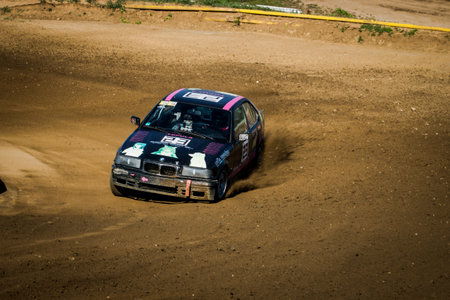 Autocross car speeding on a dirt circuit during a motorsport competition.の写真素材