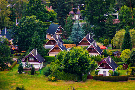 Scenic view of small holiday cottages with gable roofs surrounded by trees and gardens in a countryside area.の写真素材