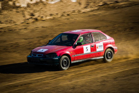 Fast-moving autocross car captured in motion on a dusty track during motorsport racing.の写真素材