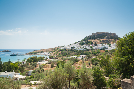 Distant view at Lindos Town and Castle with ancient ruins of the Acropolis on sunny warm day. Island of Rhodes, Greece. Europe.の写真素材