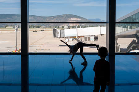 05/26/2019. Bodrum Airport / Milas Mugla Airport. Turkey. Small girl doing cartwheels exercise out of boredom while awaiting for her flight.のeditorial素材