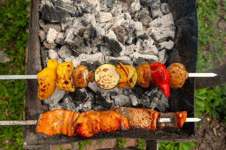 Variety of meat, fish and vegetable ingredients put on metal skewers and placed over charcoal grill.