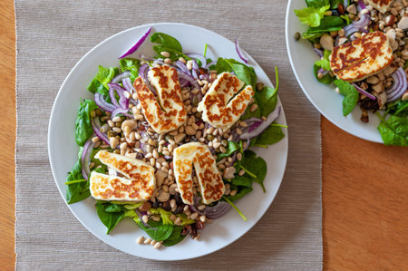 Fresh and healthy vegetable salad with chunks of grilled halloumi goat cheese on top.