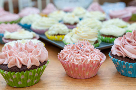 Home baked cupcakes beautifully decorated with buttercream on top placed on wooden table.の写真素材