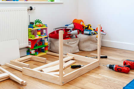 Assembling from flat-pack a set of two small chairs with desk in child's bedroom.の写真素材