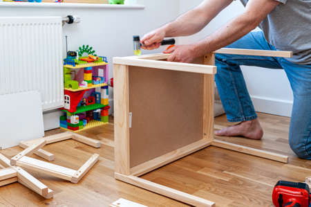 A male adult person assembling flom flat-pack a set of two small chairs with desk in child's bedroom.の写真素材