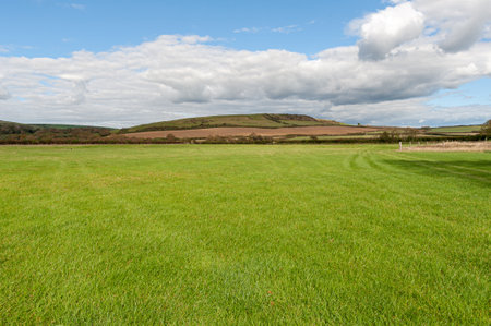 Hills with a green lush grass,fields and meadows against blue cloudy sky.の写真素材