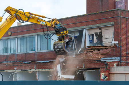 Demolition of an old building with a long reach machine hydraulic jaw. Regeneration of a space for new, modern building.の写真素材