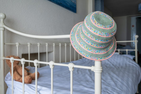 Colorfull summer hat on bed frame with teddy bear plush toy.