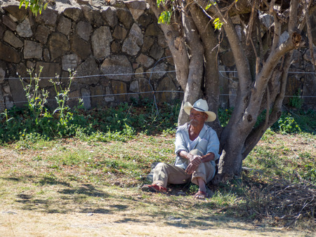 Monte Alban, Oaxaca, Mexico, South America - January 2018: [Mexican man in hat laying under tree, resting, selling souvenirs, sombrero]のeditorial素材