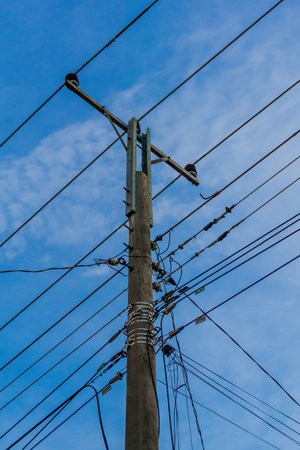 A powerful image of tangled power lines against a clear blue sky, showing the complexity of modern...