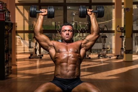 male bodybuilder doing shoulder press whit dumbbellの写真素材