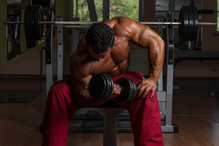 shirtless bodybuilder doing heavy weight exercise for bicepsの写真素材