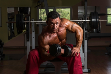 shirtless bodybuilder doing heavy weight exercise for bicepsの写真素材
