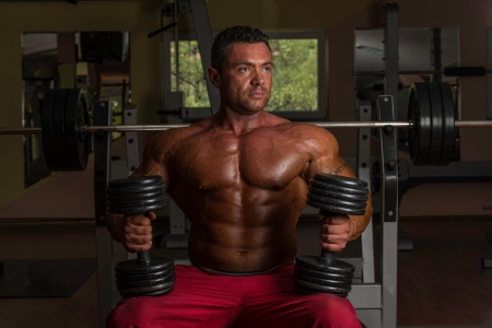 shirtless body builder posing with dumbbell at the benchの写真素材