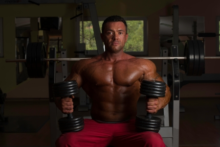 shirtless body builder posing with dumbbell at the benchの写真素材
