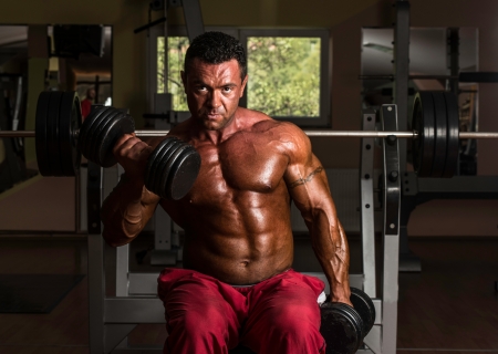 shirtless bodybuilder doing heavy weight exercise for bicepsの写真素材
