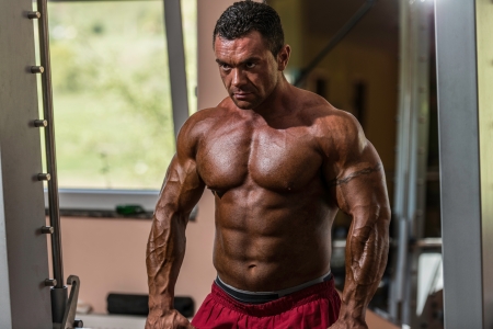 male bodybuilder doing heavy weight exercise for trapの写真素材