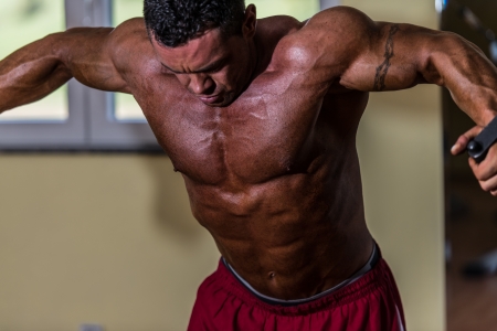 shirtless body builder doing standing press white cable for chestの写真素材